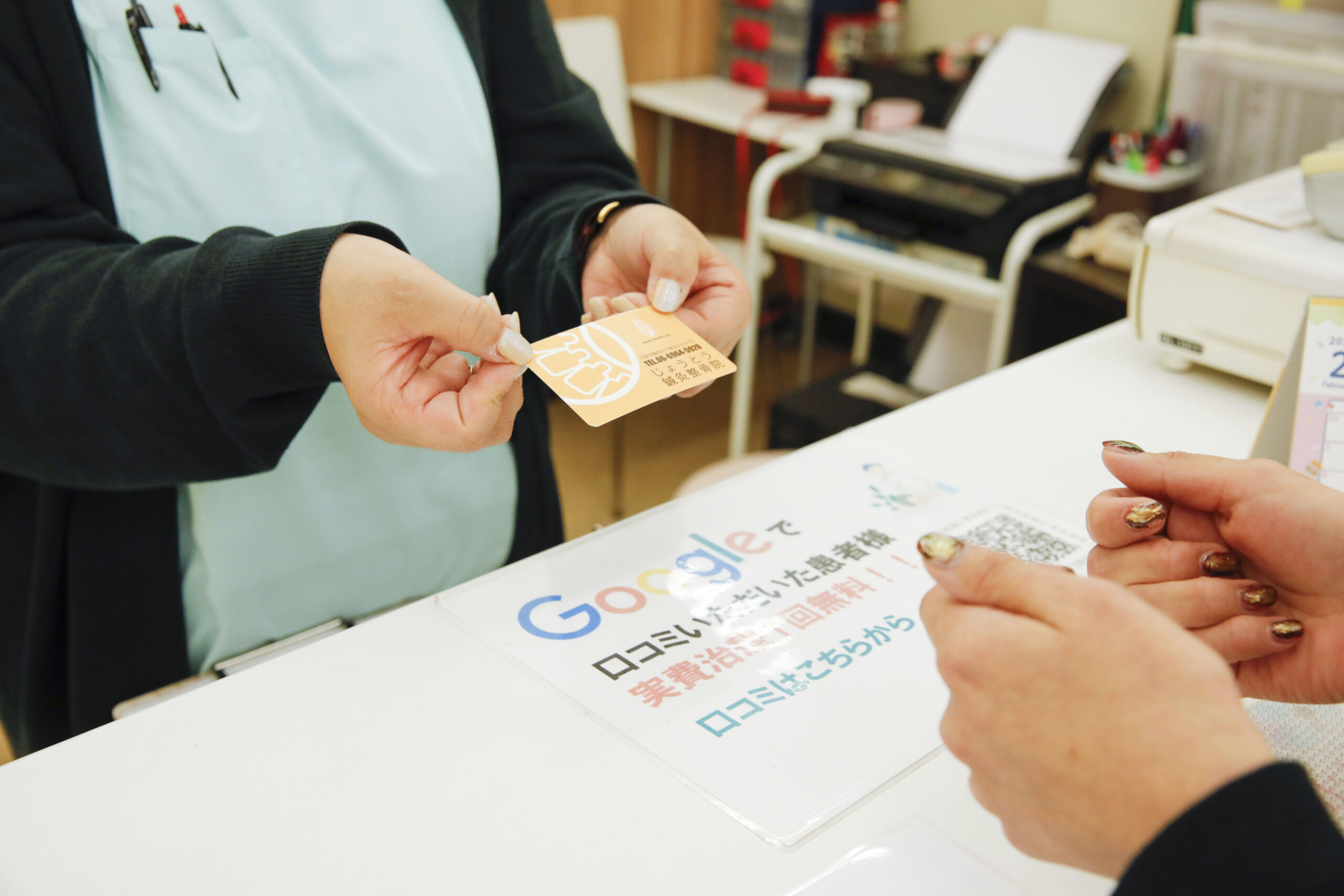 診察券を手渡す山田さんズームアップ
