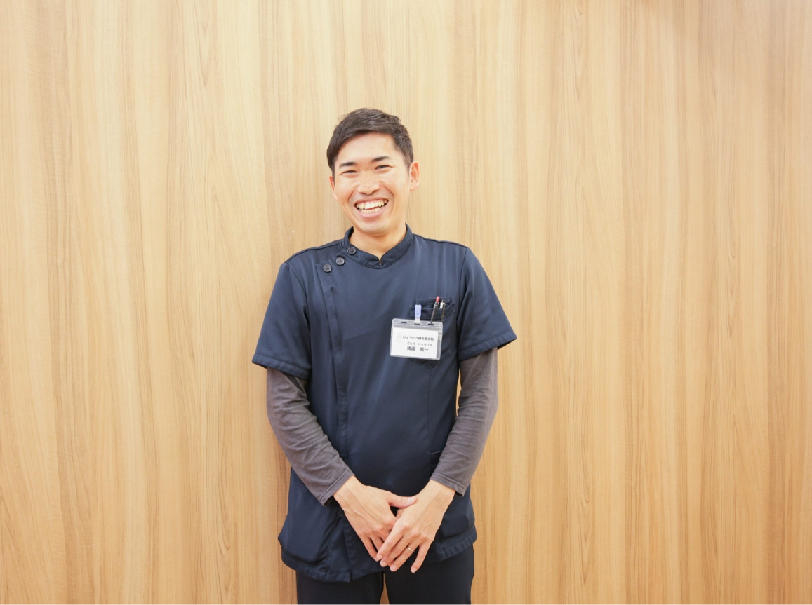 壁を背に立つ後藤さん